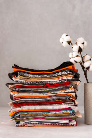 Various natural kitchen napkins stacked close up, cotton branch in concrete vaseの写真素材