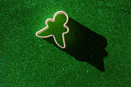 Shape for christmas gingerbread man cookie on bright green background with shadow under sunlightの写真素材