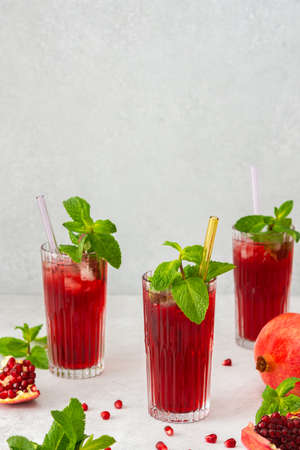 Refreshing pomegranate juice in glasses with mint and glass straw, cold drinkの写真素材