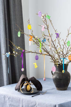 Blooming cherry branches decorated with colorful ribbons with Easter eggs, Happy Easter, table setting, napkin and egg rabbitの写真素材