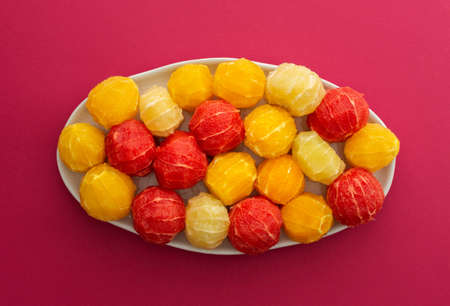 Peeled grapefruits, oroblancos and oranges close-up in an oval dish, top view of citrus fruits on a pink backgroundの写真素材