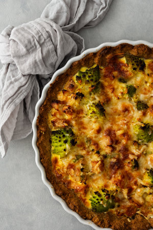 Homemade baked pot pie with Romanesco cabbage, chicken breast and cheese in a round ceramic baking dish on a gray background, top viewの写真素材