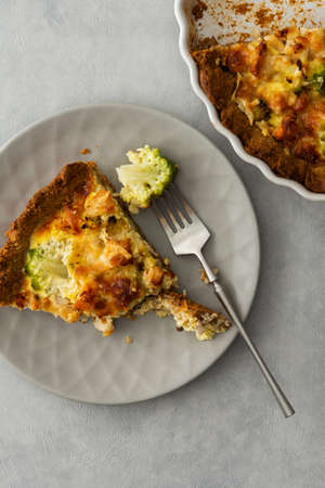 Homemade baked pot pie on a gray background, piece of pot pie with Romanesco cabbage, chicken breast and cheese on a plate, top viewの写真素材