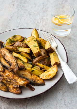 Hearty dinner, baked potatoes with dill and flour-fried capelin, top viewの写真素材