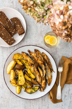 Hearty dinner, baked potatoes with dill and flour-fried capelin, top viewの写真素材