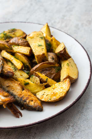 Hearty dinner, baked potatoes with dill and flour-fried capelin close upの写真素材