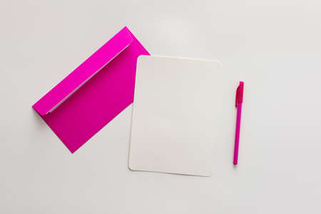 Pink envelope with blank paper and pen, greeting card or invitation mockup, top view, copy spaceの写真素材