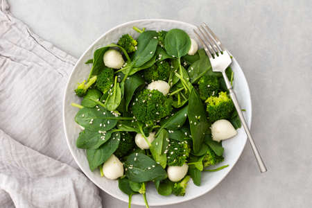 Delicious light salad with spinach, mozzarella and broccoli sprinkled with sesame seeds, top viewの写真素材