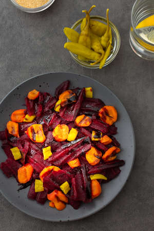 Warm salad with boiled carrots and beetroot and green peppers, water with lemonの写真素材
