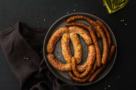 Baked pork sausages with spices in a plate close-up on a dark backgroundの写真素材