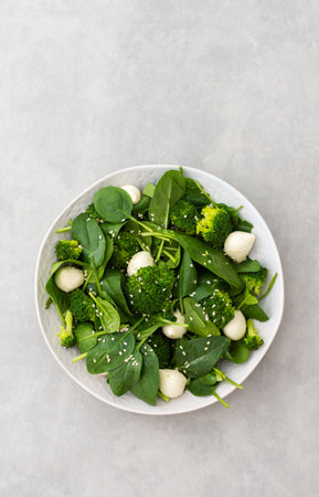Delicious light salad with spinach, mozzarella and broccoli sprinkled with sesame seeds, top viewの写真素材