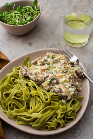 Green pasta from durum wheat and gravy with champignons fried in sour cream sauce with green onions...