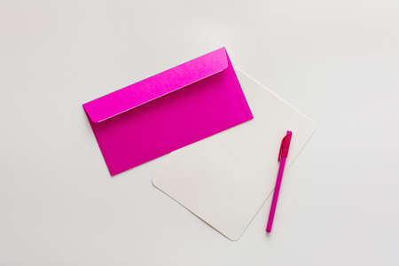 Pink envelope with blank paper and pen, greeting card or invitation mockup, top view, copy spaceの写真素材