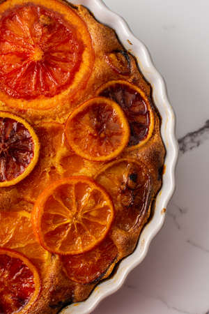 Sweet pie with caramelized citrus fruits in a round ceramic form, top viewの写真素材