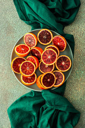 Halves of a blood orange in a plate on a green tablecloth, top viewの写真素材