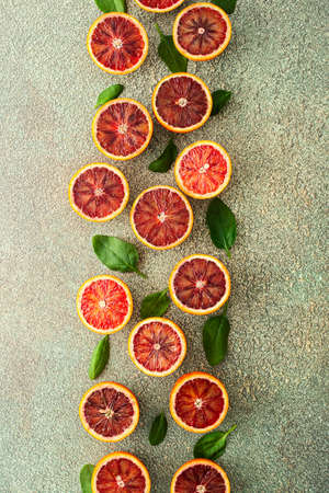 Half cut blood orange halves with spinach leaves on a green background, top viewの写真素材