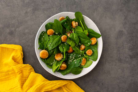 Delicious light salad with spinach and fried champignon mushrooms sprinkled with sesame seeds, top viewの写真素材