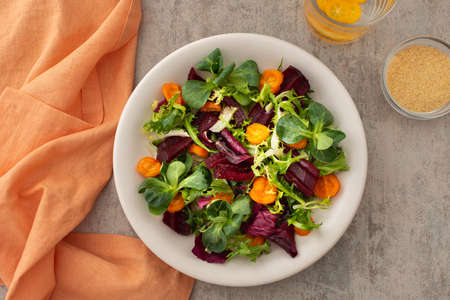 Warm salad with mixed salad with boiled carrots and beetroot with spices, water with kumquatの写真素材
