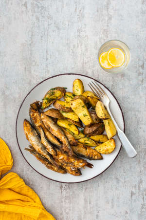 Hearty dinner, baked potatoes with dill and flour-fried capelin, top viewの写真素材