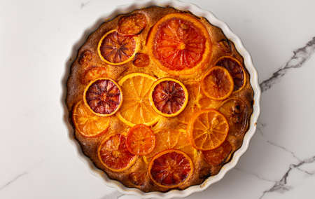 Sweet pie with caramelized citrus fruits in a round ceramic form, top viewの写真素材