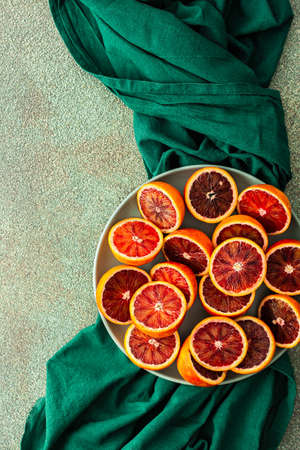 Halves of a blood orange in a plate on a green tablecloth, top viewの写真素材