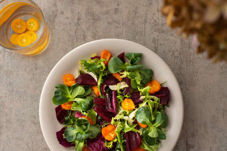 Warm salad with mixed salad with boiled carrots and beetroot with spices, water with kumquatの写真素材