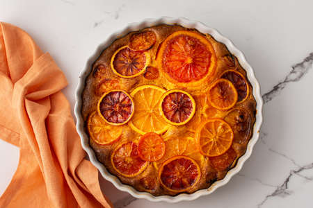 Sweet pie with caramelized citrus fruits in a round ceramic form, top viewの写真素材