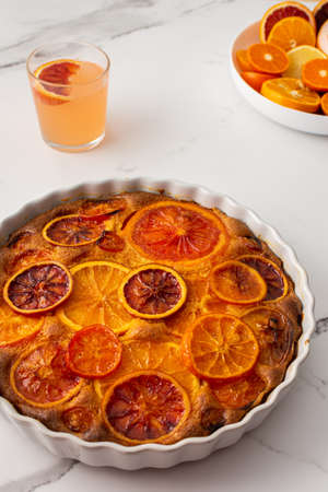 Sweet pie with caramelized citrus fruits in a round ceramic form, top viewの写真素材