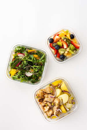 Home cooked food in lunch boxes for office, healthy eating at work and office food, new potatoes with chicken breast, salad and sliced fruits and berries, top viewの写真素材