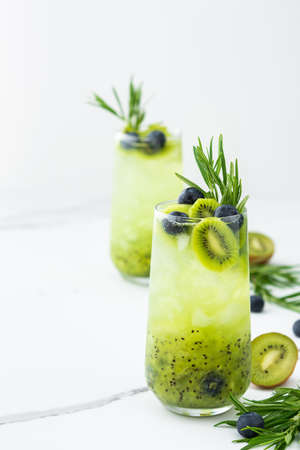 Refreshing drink with kiwi smoothie, summer sweet fruit juice with blueberries and rosemaryの写真素材