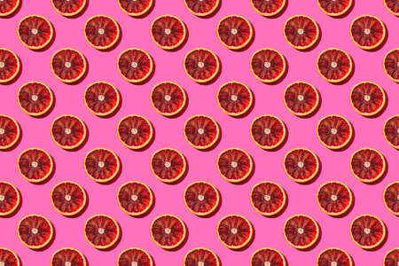 Seamless fruit pattern with round blood orange slices on a bright pink background, pop art style of the sixtiesの写真素材
