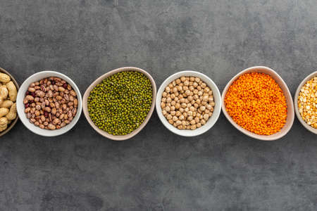 Different types of legumes in bowls, yellow peas and chickpeas , beans and peanuts, maash and lentils, top view, copy spaceの写真素材