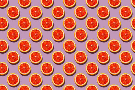 Seamless pattern with round slices of blood orange on a soft lilac background, pop art style of the sixtiesの写真素材