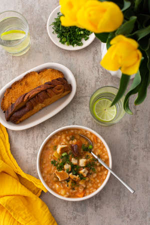Soup with barley and sauerkraut, a plate with soup and croutons, top view on the table with food and a vase with tulips, delicious healthy lunch, Russian cuisineの写真素材