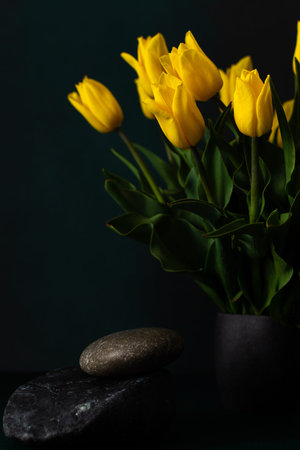 Beautiful spring bouquet of yellow tulips in a vase on a dark background, festive bouquet for...
