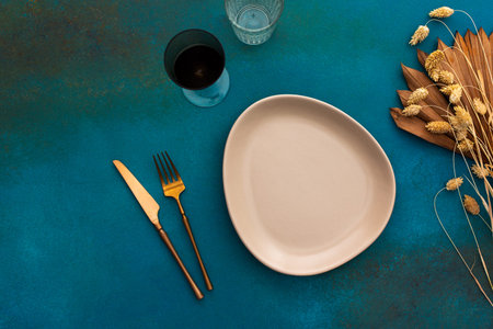 Table setting, empty plate and cutlery on turquoise background, top view of served table decorated...