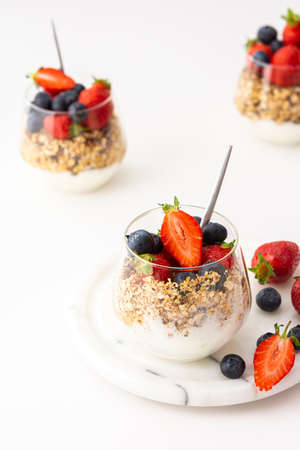 Homemade granola with almonds in a glass with yogurt, fresh strawberries and blueberries, delicious healthy breakfastの写真素材