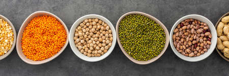 Banner of different types of legumes in bowls, yellow peas and chickpeas , beans and peanuts, maash and lentils, top view, copy spaceの写真素材