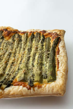 Baked puff pastry pie with cheese and asparagus on a white background, top view, copy spaceの写真素材