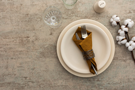 Table setting, plate with napkin and cutlery on a brown background, top view of the served table...