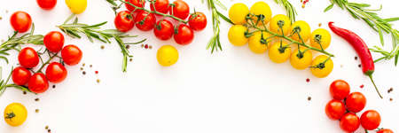 Yellow and red tomatoes, hot peppers, rosemary and spices on a white background, food banner, top view, copy spaceの写真素材