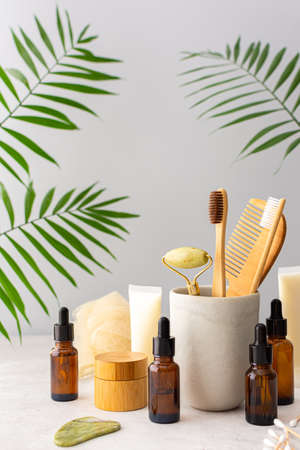 Wooden toothbrushes with natural bristles in a ceramic glass, face and skin care products, bottles with a pipette and a jar of cream, bath accessories, spa and beauty conceptの写真素材