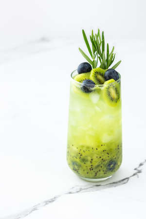 Refreshing drink with kiwi smoothie, summer sweet fruit juice with blueberries and rosemaryの写真素材