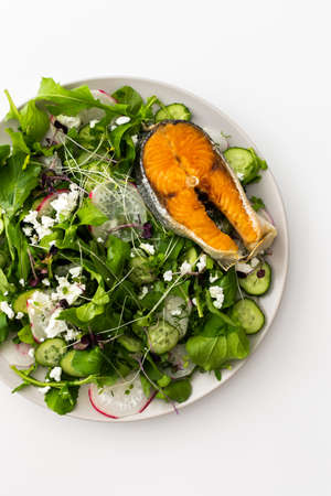 Delicious light salad with cucumbers and arugula, feta and microgreens, radishes and dill, fried salmonの写真素材