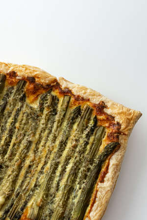 Baked puff pastry pie with cheese and asparagus on a white background, top view, copy spaceの写真素材