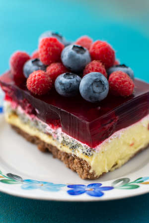 A piece of cake with poppy seeds and berry jelly, cake on a plate decorated with juicy raspberries and blueberriesの写真素材