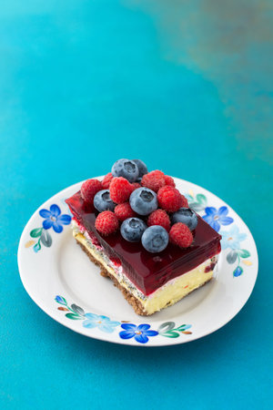 A piece of cake with poppy seeds and berry jelly, cake on a plate decorated with juicy raspberries...