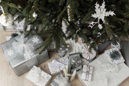 Decorated Christmas tree with balls and flowers of white decorative poinsettia, gift boxes with bows under the tree, Merry Christmas and Happy New Yearの写真素材