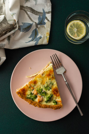 Homemade pie with red fish and broccoli, quiche with salmon and char, cheese and cream, portion of pie on a plateの写真素材