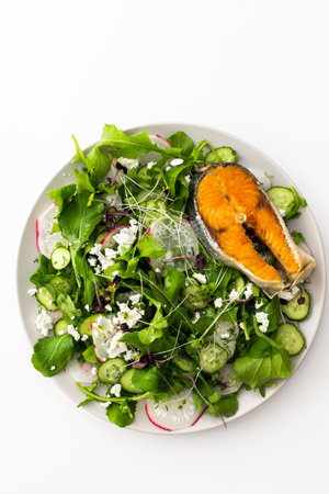 Delicious light salad with cucumbers and arugula, feta and microgreens, radishes and dill, fried salmonの写真素材